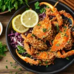 Fried soft shell crab garnished with herbs and lemon slices.