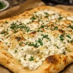 A freshly made cottage cheese flatbread served on a wooden board with garnishes like parsley and a side of creamy dip.