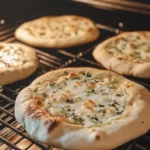 Burnt cottage cheese flatbread on a baking sheet alongside a perfectly baked flatbread, showing the effects of high oven temperature.